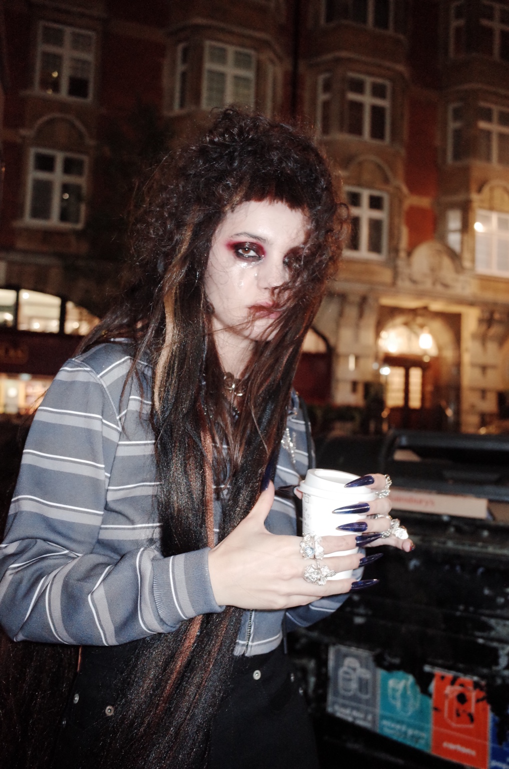 Among Others, figure holding a takeaway coffee on a London street at night