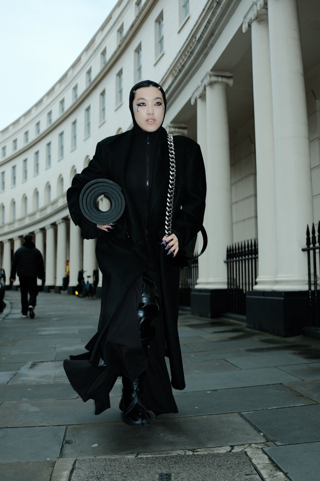 A figure carrying a rolled yoga mat through the city