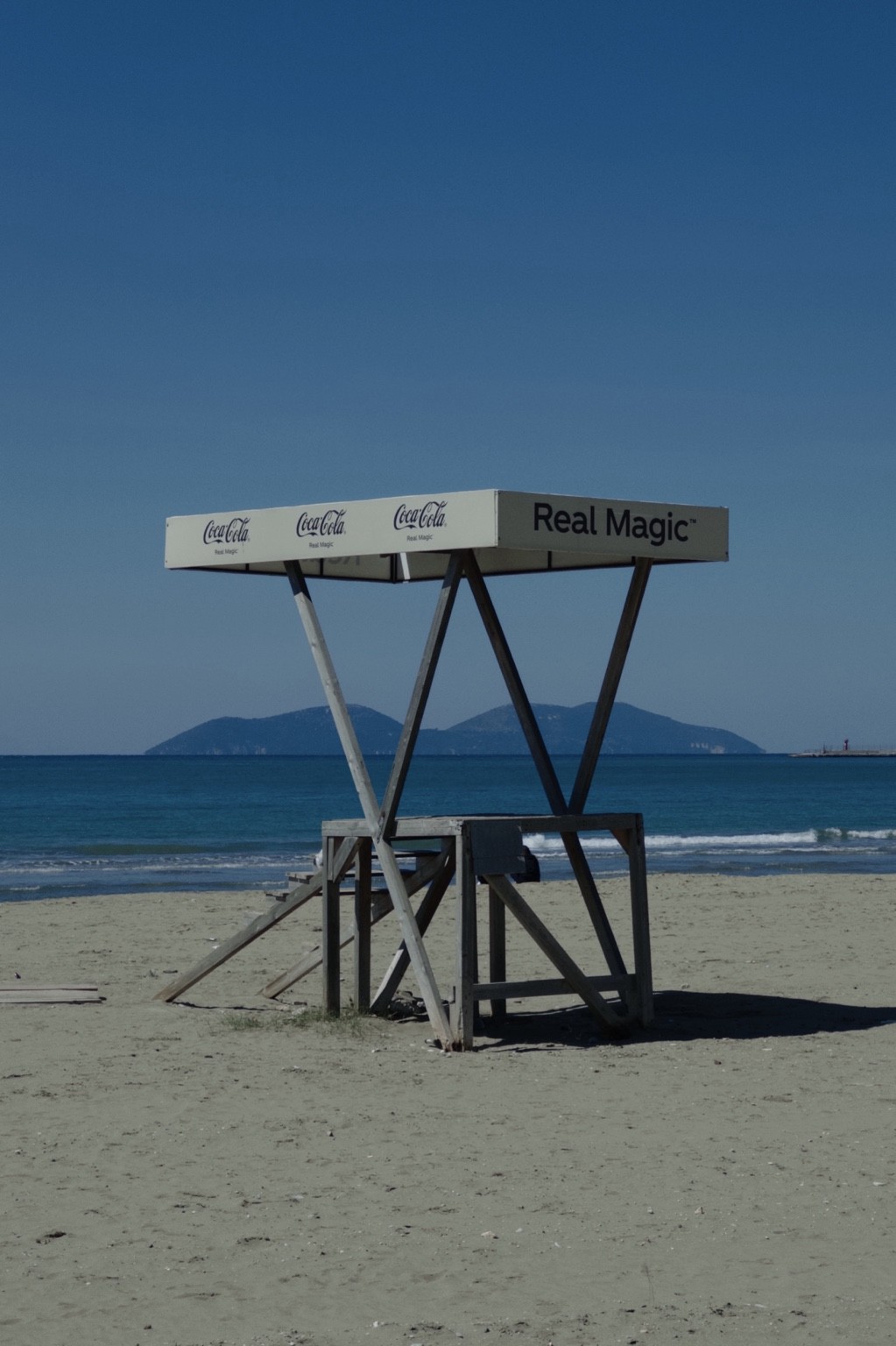 Gaze, empty beach structure marked Real Magic with sea and island beyond