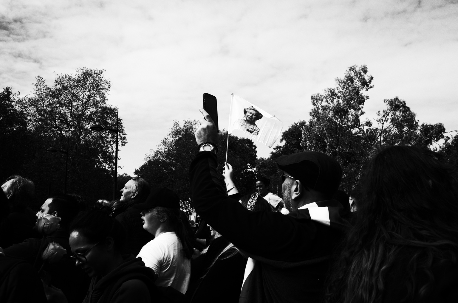 Crowd, raised phone and printed image during public mourning in London, 19 September 2022