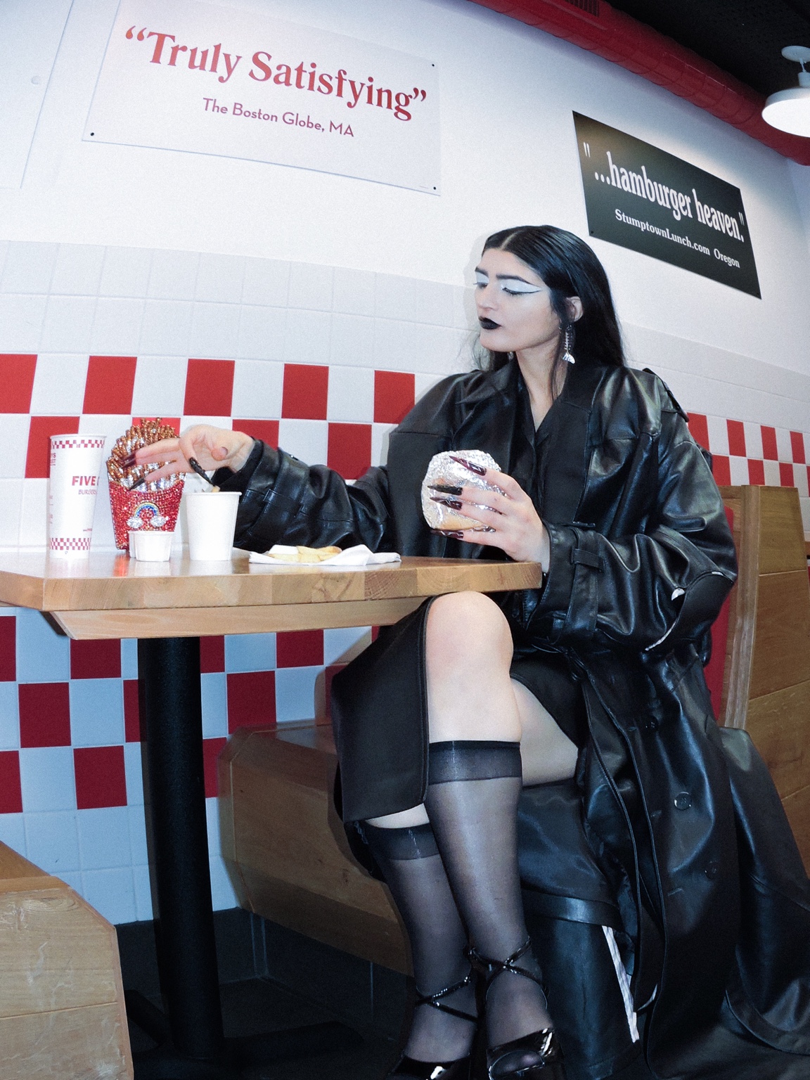 Dressed figure seated in a fast-food restaurant, London, 26 October 2023