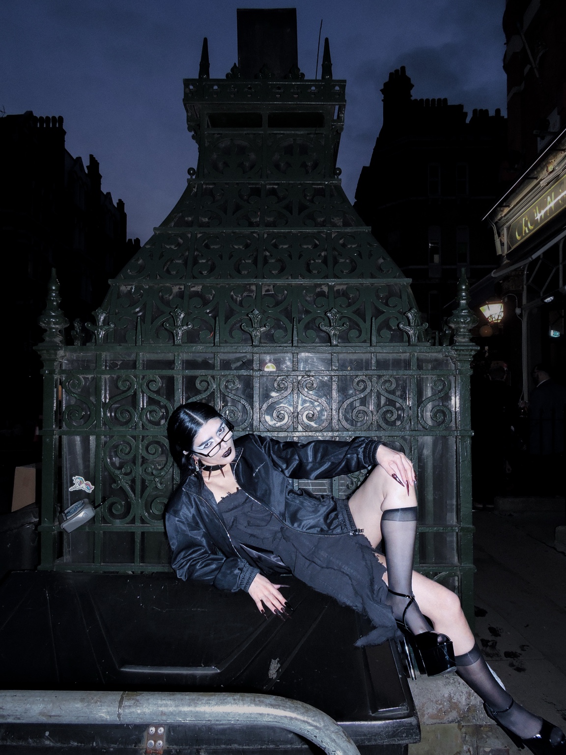 Dressed figure posed at night, London, 26 October 2023