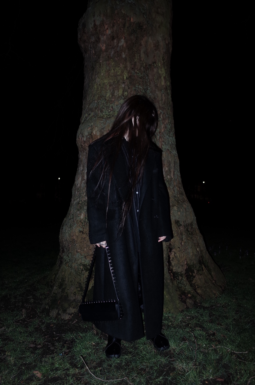 Figure standing against a tree at night, London, 16 February 2024