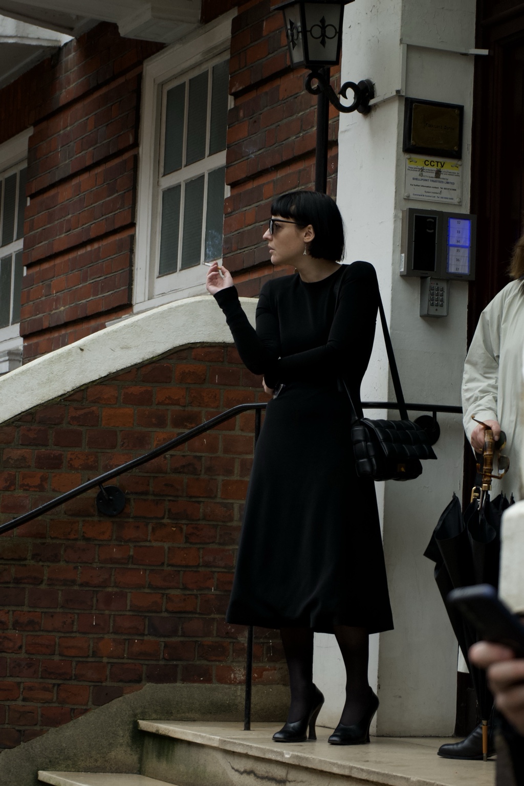 Black-dressed figure smoking outside the LOEWE show, London, 18 February 2024