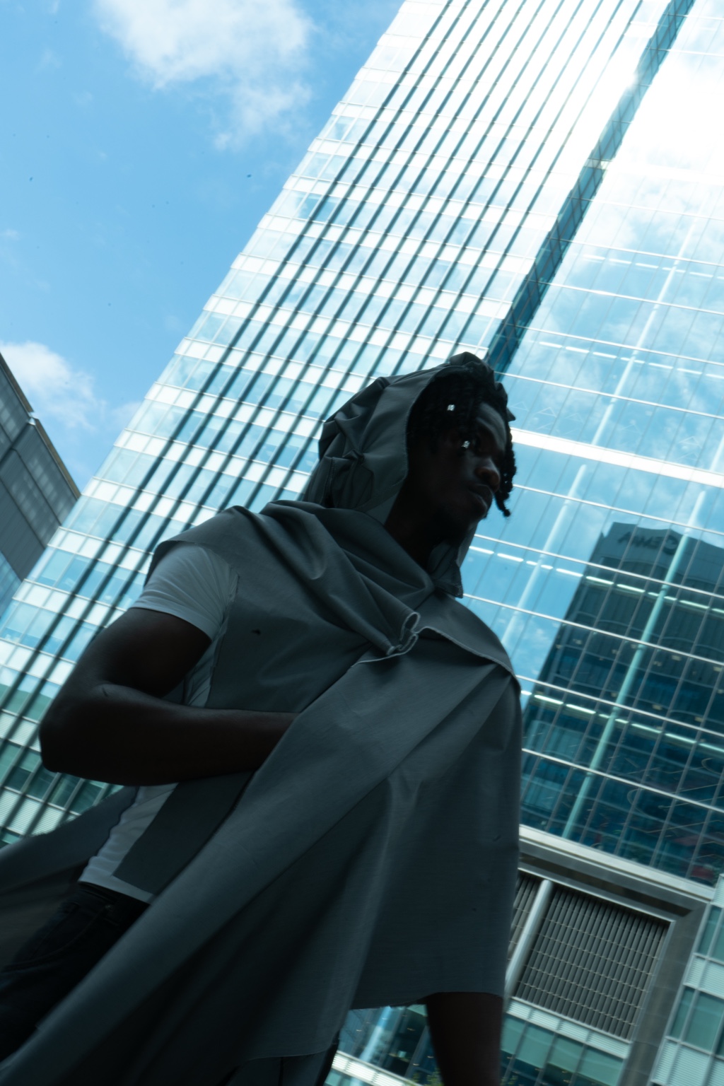 Dressed figure seen against glass towers, London, 26 April 2024