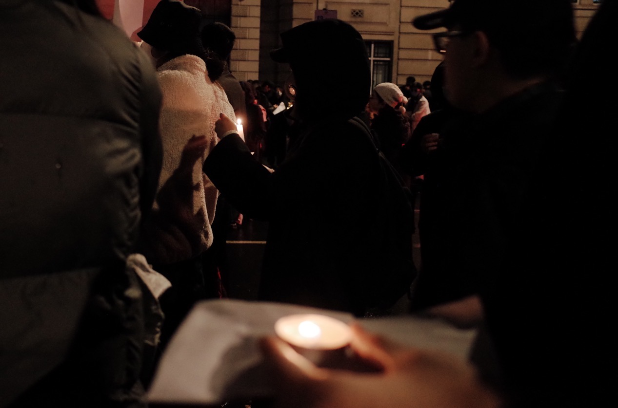 Candle held within a night crowd, London, 27 November 2022